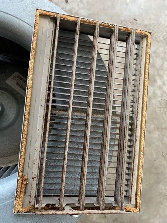 Rusty, dust-lined supply register pulled for cleaning